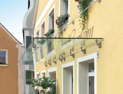 Glasvordach an einem gelben Gebäude.