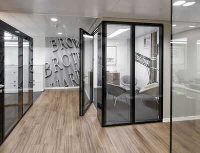 Büro mit Glaswänden, schwarzen Rahmen und Holzboden