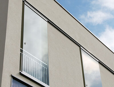 Fassade eines modernen Gebäudes mit großen Glasschiebetüren und Balkongeländern.