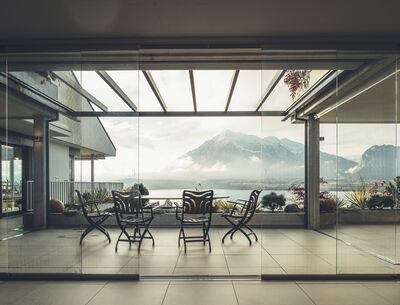 Terrasse mit Glaswänden und einer spektakulären Aussicht auf eine Berglandschaft.